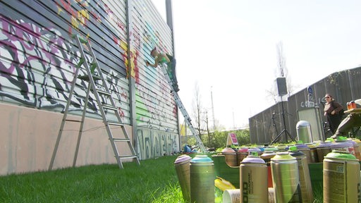Graffitykünstler srayen auf der eine Laermschutzwand