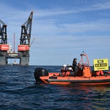 Ein Schlauchboot von Greenpeace mit einem "No new Gas!"-Banner fährt vor der Bohrinsel in Borkum.