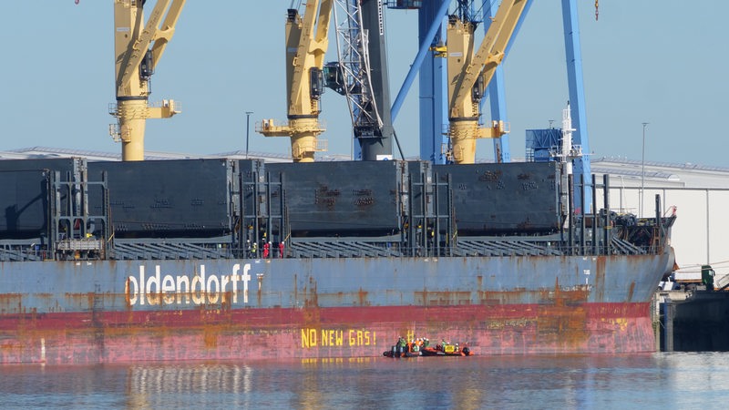 Zwei Schlauchboote von Greenpeace fahren an ein Containerschiff in Brake und schreiben eine Botschaft an den Rumpf.