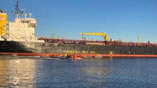Schlauchboote fahren neben einem Tanker auf der Weser