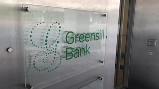 Das Schild der Greensill Bank mit dem Logo daneben.