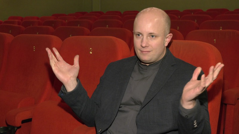 Matthias Greving sitzt in einem Kinosessel.