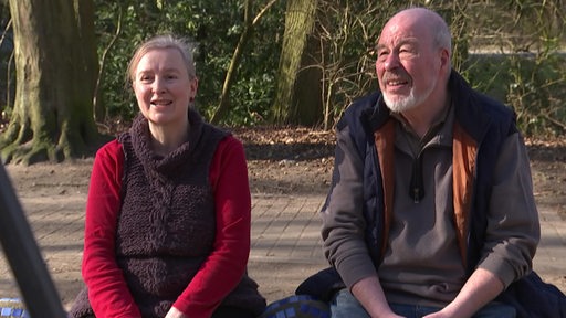 Ein älteres Ehepaar wird auf einem Spielplatz interviewt.