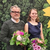 Ein Mann und eine Frau stehen vor einem grünen Hintergrund nebeneinander