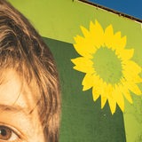 Die Ecke eines Wahlplakats der Grünen mit Sonnenblume ist zu sehen.