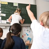Schüler einer Grundschule arbeiten in einem Klassenzimmer an Mathematikaufgaben.
