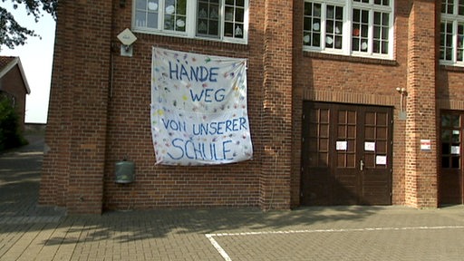Ein Transparent mit der Aufschrift "Hände weg von unserer Schule" an der Grundschule in Bremen-Strom.