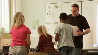 Ein männlicher Lehrer unterrichtet eine Grunschulklasse.