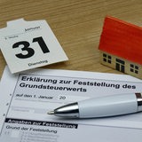 Eine Spielzeughaus neben einer Grundsteuererklärung.