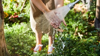 Eine Frau wäscht ihre Hände im Garten