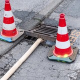 Ein Schlauch leitet Flüssigkeit in einen Gully.