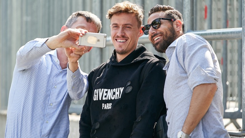 Werder-Spieler Max Kruse und Claudio Pizarro machen mit einem Mann lachend ein Selfie