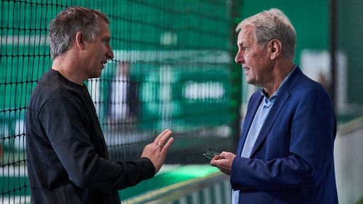 Frank Baumann und Jörg Wontorra unterhalten sich am Rande einer Werder-Veranstaltung in einer Indoor-Fußballhalle.