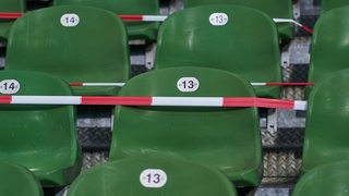 Grüne Sitzreihen auf der Tribüne des Weser-Stadions, die mit rot-weißem Absperrband umwickelt sind.