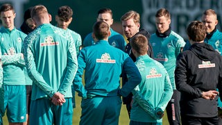 Werder-Coach Florian Kohfeldt hält beim Training eine Ansprache, umringt von seinen Spielern.
