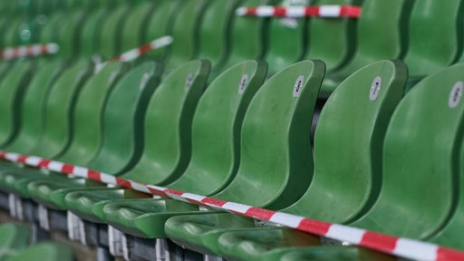 Grüne Sitzreihen im Weser-Stadion sind mit rot-weißen Absperrband überzogen.