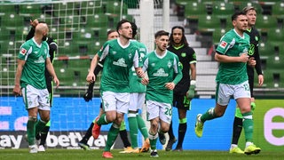 Mehrere Werder-Spieler laufen nach einem Treffer zurück zum Mittelkreis.
