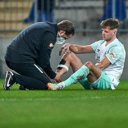 Werder-Arzt Daniel Hellermann behandelt Niclas Füllkrug am verletzten Fuß.