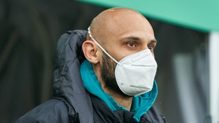 Ömer Toprak trägt eine Maske und steht in Vereinskleidung am Spielertunnel.
