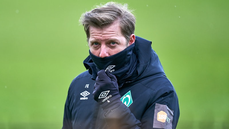 Werder-Trainer Florian Kohfeldt zieht während des Trainings seinen Schal bis über die Nase hoch.