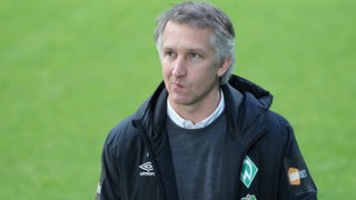 Werder-Sportchef Frank Baumann verzieht vor dem Spiel etwas nachdenklich den Mund.
