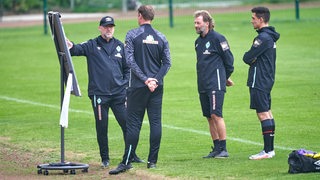 Werders Trainer-Team berät sich beim Training.  
