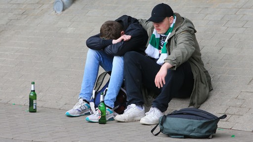 Zwei Werder-Fans hocken tief enttäuscht vor dem Weserstadion.
