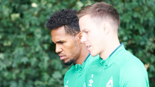 Die Werder-Kapitäne Theodor Gebre Selassie und Niklas Moisander gehen nebeneinander in Richtung Trainingsplatz.