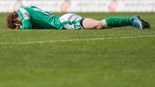 Werder-Stürmer Joshua Sargent liegt bäuchlings ausgestreckt frustriert auf dem Rasen.