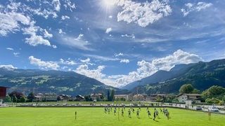 Werder-Spieler trainieren vor dem Alpenpanorama des Zillertals bei strahlendem Sonnenschein.