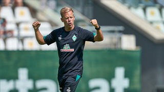 Werder-Trainer Markus Anfang reckt auf dem Trainingsplatz die Arme hoch wie ein Muskelprotz.