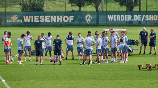 Werders Spieler und Trainer stehen auf dem Fußballplatz im Kreis.