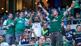 Werder-Fans stehen freudig auf der Tribüne des Weser-Stadions.