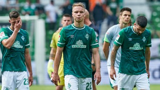 Mehrer Werder-Spieler verlassen geknickt und enttäuscht das Spielfeld.