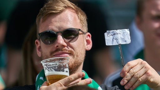 Ein Werder-Fan hält einen Zettel mit der Aufschrift "Baumann raus!" in die Höhe.