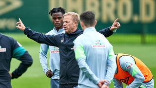 Werder-Trainer Markus Anfang erklärt mit ausgebreiteten Armen etwas beim Training.