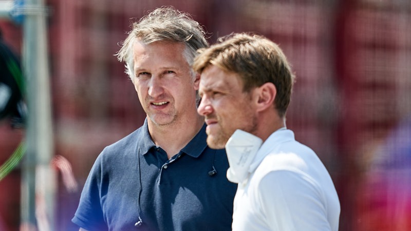 Werder-Sportchef Frank Baumann und Scouting-Chef Clemens Fritz stehen am Rande des Spiels in Karlsruhe beieinander.