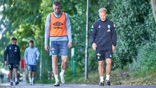Werder-Trainer Markus Anfang und Marvin Ducksch unterhalten sich auf dem Weg zum Weser-Stadion.
