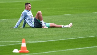 Werder-Verteidiger Marco Friedl ruht sich auf dem Rasen des Trainingsplatzes aus.