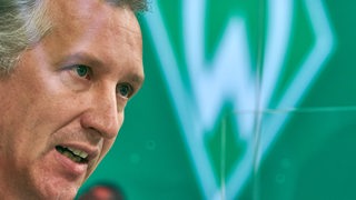 Werder-Sportchef Frank Baumann in der Nahansicht bei einer Pressekonferenz auf dem Podium.