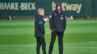 Werder-Coach Markus Anfang spricht an Rande des Trainings mit Sportchef Frank Baumann, der die Kapuze fest zugezogen hat.