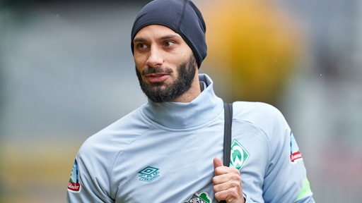 Werder-Kapitän Ömer Toprak trägt auf dem Weg zum Trainingsplatz eine schwarze Mütze.