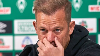 Werder-Trainer Markus Anfang fasst sich während einer Pressekonferenz ins Gesicht.