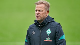 Werder-Trainer Markus Anfang mit Händen in den Taschen auf dem Trainingsplatz.