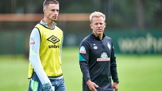 Werder-Spieler Marco Friedl geht am Rande des Trainings neben Coach Markus Anfang.