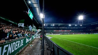 Die Werder-Fans feuern ihre Spieler im von Flutlicht erhellten Weser-Stadion an. 