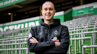 Werders neuer Trainer Ole Werner posiert mit verschränkten Armen im Weser-Stadion.