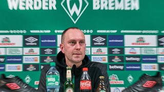 Werder-Trainer Ole Werner auf dem Podium einer Pressekonferenz.