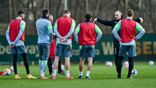 Werder-Coach Ole Werner erklärt gestikulierend etwas seinen Spielern am Rande des Trainings.