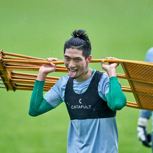 Werder-Spieler Kyu-Hyun Park schleppt die Metallmännchen auf dem Rücken vom Trainingsplatz und streckt kess die Zunge in die Kamera.